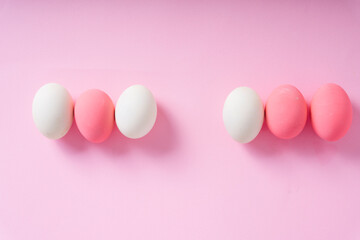 Top view - Group of white and pink eggs over pink background.