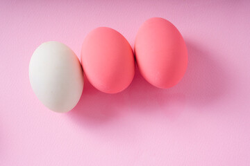 Top view - Group of white and pink eggs over pink background.