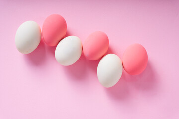 Top view - Group of white and pink eggs over pink background.