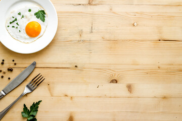 Fried eggs on plate - light wooden dinner table from above copy space