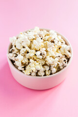Popcorn in a pink bowl on pink background 45 degree angle close-up shot