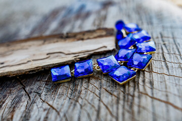 Costume jewelry for a festive day, long earrings with large square blue stones and an ultramarine bracelet. Elegant accessories on a dry wooden surface on natural elements