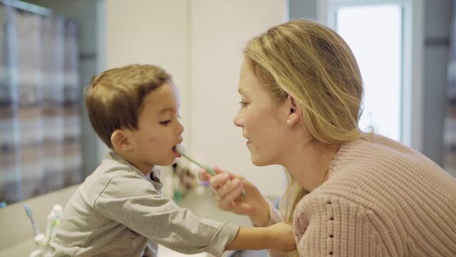 MS Smiling mother brushing son's (2-3) teeth in bathroom / Denmark
