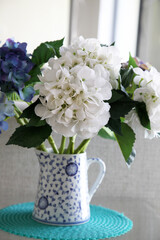 Fototapeta na wymiar Beautiful white and blue imitation hydragrea flowers in blue and white vase