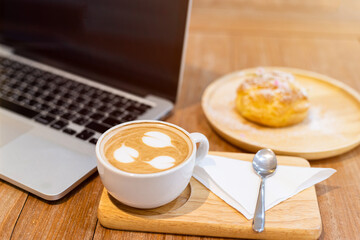Close-up of with coffee cup working with laptop computer and Homemade profiteroles with Choux Cream in coffee shop like the background,Snack during work concept