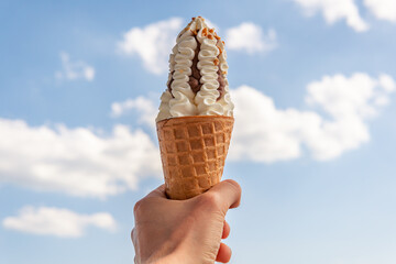 Big tasty yummy and beautiful ice-cream with nuts and crunchy cone in a hand