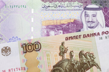 A close up image of a one hundred Russian ruble bank note close up with a five Saudi riyal bank note