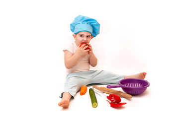 A little boy in a chef's hat cooks in a toy kitchen on a white background
