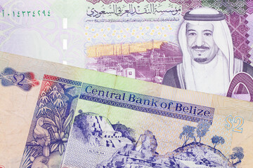 A colorful two dollar bill from Belize in close up macro with a colorful five riyal, Saudi Arabian bank note