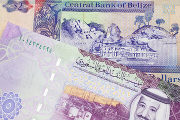 A colorful two dollar bill from Belize in close up macro with a colorful five riyal, Saudi Arabian bank note