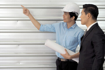 Asian businessman and architect or engineer with helmet are discussing work together at construction site.