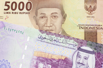 An orange five thousand Indonesian rupiah bank note with a five riyal note from Saudi Arabia