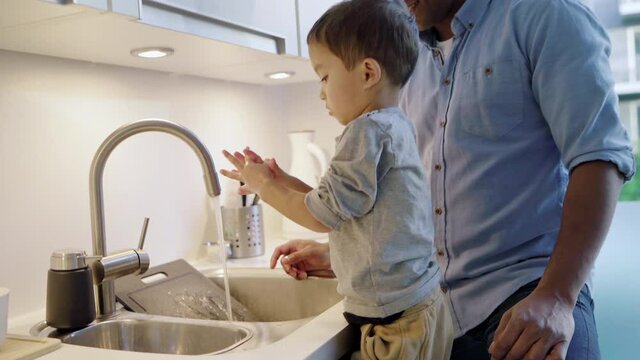 MS Father assisting son (2-3) washing hands at kitchen sink / Denmark