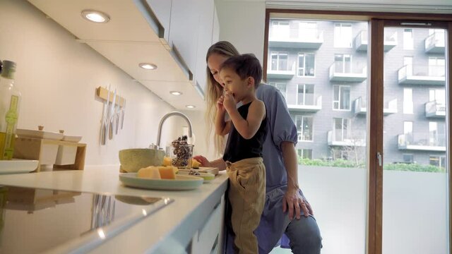 MS Mother assisting son (2-3) preparing dessert in kitchen / Denmark