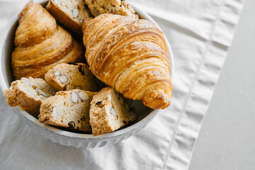 Freshly baked classic croissants and almond biscottis on linen light background. Breakfast food concept. 