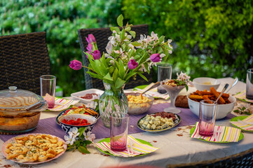 Lunch in the open air. Many dishes on the table. Table decorated with flowers. Table food variety concept.