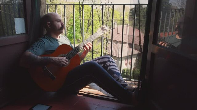 MS Man playing acoustic guitar on balcony / Milan, Italy