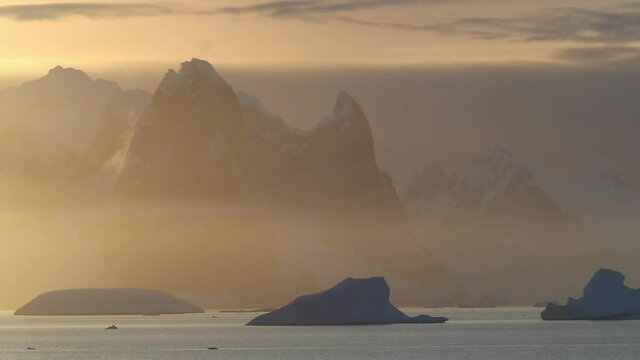 WS Snow covered mountains and Lemaire Channel in fog at sunrise / Antarctic Peninsula, Antarctica