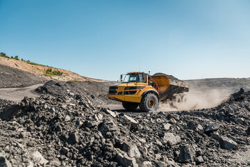 Obraz na płótnie Canvas Large quarry dump truck. Loading the rock in dumper. Loading coal into body truck. Production useful minerals. Mining truck mining machinery, to transport coal from open-pit excavator work