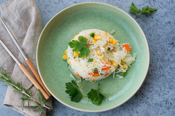 Cooked rice with vegetables on a grey concrete background, home-cooked food, top view