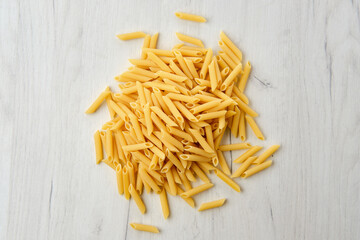 Overhead view of penne pasta on wooden background