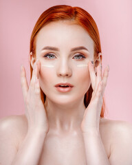 Red-haired girl on a pink background. Portrait of a beautiful healthy girl with clean skin and natural makeup on a pink background. Beauty concept.