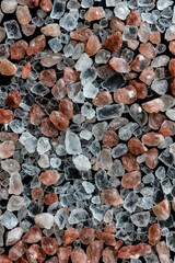 Pink and white himalayan salt crystals on black background. Handful of salt crystals, top view. Vertical background wallpapers.