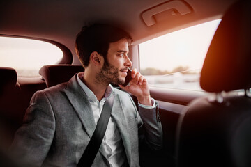 Young man sitting in the car and talking on a phone