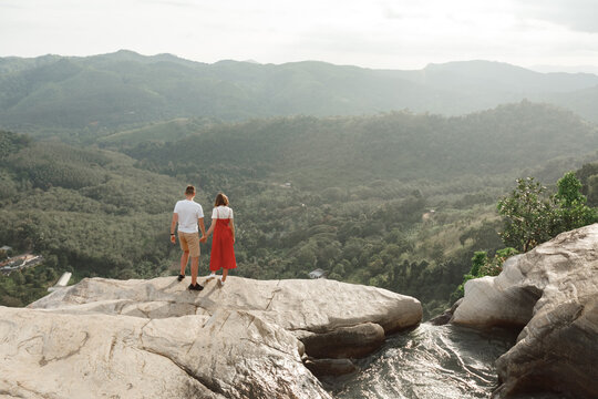 Couple of  travel bloggers explore beautiful places in Sri Lanka island. Man ad woman on mountain cliff to the jungle, serene landscape of Diyaluma falls