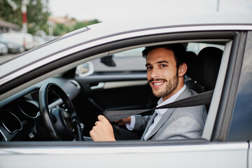 Fototapeta na wymiar Businessman in his car fastening the seatbelt, safe driving concept