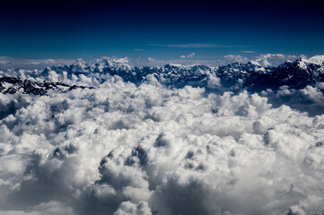 Naklejka na ściany i meble Aerial view of the Himalayas mountain ranges covered in snow and clouds