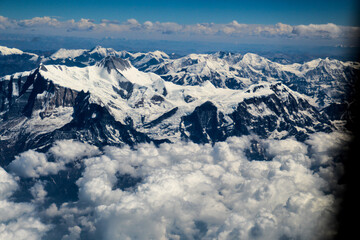Fototapeta na wymiar Aerial view of the Himalayas mountain ranges covered in snow and clouds as seen from an airplane window