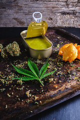 marijuana buds. medical cannabis butter in a open tin can. hemp leaves. vertical orientation.