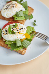 Breakfast toast with poached egg and avocado on the white plate