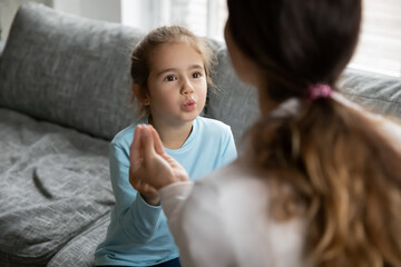 Small preschooler disabled girl practice nonverbal talk with female nanny or tutor at home, cute little child make hand gesture learn speak sign language with mother, children disability concept