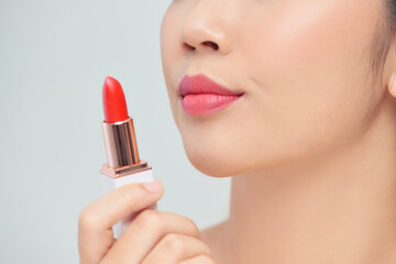 Beautiful young woman applying red lipstick on color background, closeup