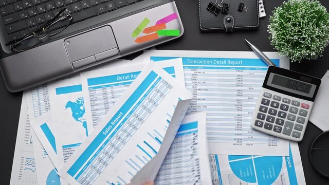 Top view of businessman working with financial statements. Modern black office desk with notebook, calc, pen and a lot of things. Flat lay table layout.
 