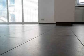 low angle horizontal view of a new black ceramic tile floor in a bright white light apartment