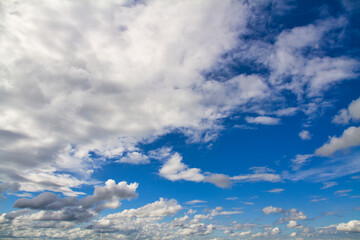 Cloudscape. Blue sky and grey clouds. Sunny day. Cumulus clouds.