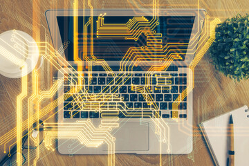 Obraz premium Computer on desktop in office with technology theme hologram. Multi exposure. Tech concept.