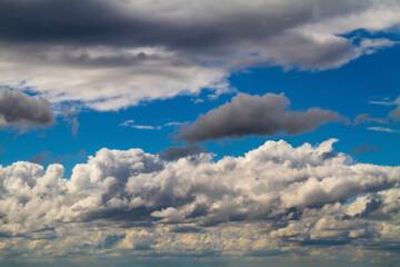 Naklejka na ściany i meble Cloudscape. Blue sky and grey clouds. Sunny day. Cumulus clouds.