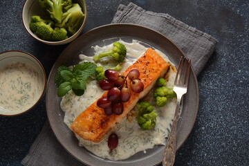 Grilled salmon with roasted red grapes and broccoli in creamy garlic sauce. Tuscan sea food recipe. Italian  gourmet cuisine. Healthy food concept. Omega -3, Keto diet