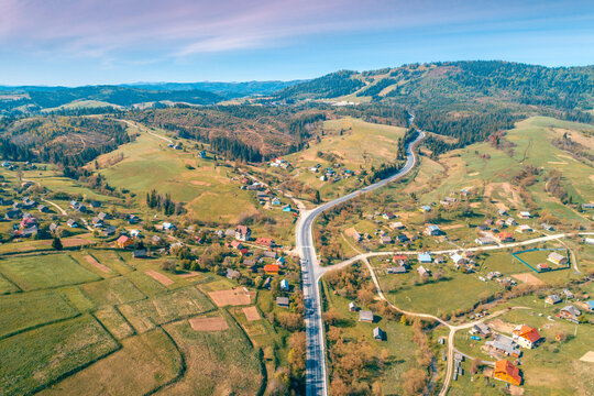 Panoramic aerial view of the mountain highway and village in spring. Beautiful skyview countryside landscape. Carpathian mountains. Ukraine