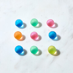 Square pattern from hydrogel colored balls on a grey marble table.