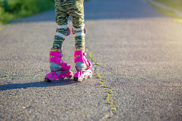 Childrens feet in pink childrens rollers close-up. Roller skates for outdoor sports. Healthy lifestyle baby