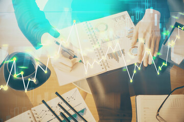 Multi exposure of hands making notes with forex chart huds. Stock market concept.