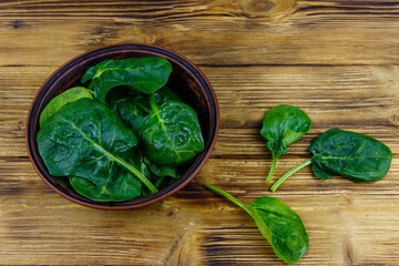 Fresh green spinach leaves in bowl on a wooden table. Top view