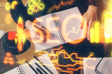 Multi exposure of woman's hands making notes with SEO icon. Concept of Search engine optimization