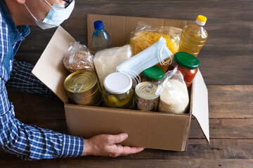 Cardboard box with oil, canned food, cereals and pasta.