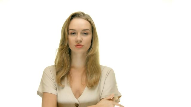 The young woman puts a finger to her lips. Hides a secret. A woman is standing against a white background. Movie for advertising with copy space.